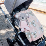 Stroller with a pink blanket and koala toy on a wooden deck.