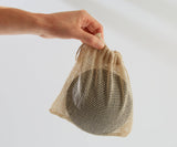 Hand holding a mesh drawstring bag with a white background