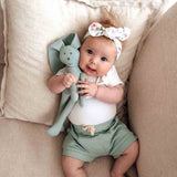 Baby holding a soft toy on a beige couch