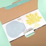 Open book with illustrations of a blue flower and yellow plant on a green background
