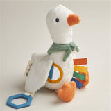 Plush toy duck with colorful patches and a blue tag on a light background