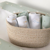 Woven basket with baby clothes on a soft surface