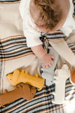 Baby playing with silicone teethers on a striped blanket
