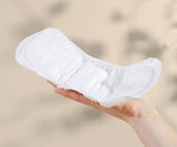 Hand holding a white sanitary pad against a blurred beige background