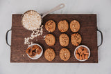 Wooden tray with cookies, oats, and almonds on a marble background