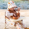 Child playing with ceramic bowls and spoons on a beach