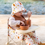 Child playing with ceramic bowls and spoons on a beach