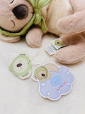 Plush dog toy with a green bandana and two cute animal stickers on a white background
