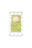 Baby doll in a floral outfit inside a white crib on a white background