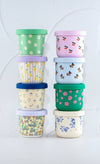 Stack of colorful patterned containers with lids on a light gray background