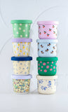Stack of colorful patterned containers with lids on a light gray background