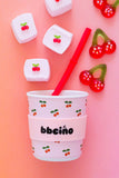 Paper cup with cherry design and marshmallows on a pink background