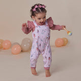 Child wearing a pink floral outfit with balloons in the background