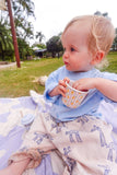 Child holding a cup outdoors with a blurred background