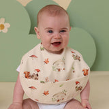 Baby wearing a bib with nature-themed print against a green background