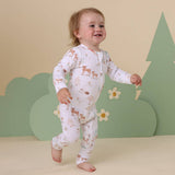 Child wearing a white onesie with animal prints against a green and beige background
