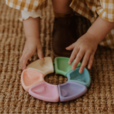 Child's hands interacting with a colorful plastic toy on a woven surface