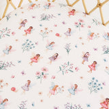 Fitted sheet with fairy and floral pattern on a crib.