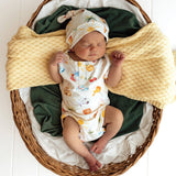 Newborn baby in a basket with a colorful outfit and hat