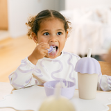 Child drinking from a sippy cup with a straw in a casual indoor setting