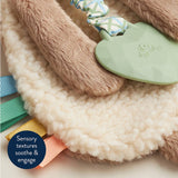 Close-up of a soft toy with textured elements on a fluffy surface, featuring sensory texturalsoothe & engage.