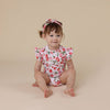Child wearing a floral outfit on a beige background