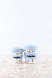 Two baby cups with blue lids on a wooden surface and white wooden panel background