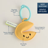Yellow baby teether with blue ring and smiley face on a light gray background