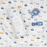 Organic muslin swaddle with baby toys on a patterned background