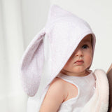 Baby wearing a white hooded towel with bunny ears on a plain background