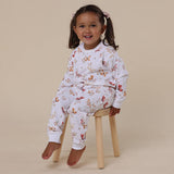Child wearing a floral pajama set sitting on a stool against a beige background
