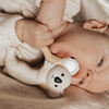 Baby holding a white toy with a face, lying on a textured surface