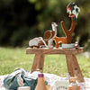 Wooden animal figurines on a small wooden table outdoors.