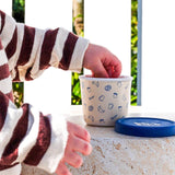 Person reaching into a small white container with blue patterns on a stone surface.