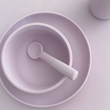 Set of purple bowls and spoon on a light gray background