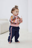Child wearing a colorful sweater and navy pants with red stripes indoors.