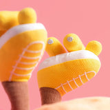 Yellow baby shoes with white soles on a pink background