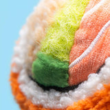 Close-up of a colorful fabric ball with green, orange, and white patterns on a light blue background.