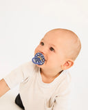 Baby with a blue pacifier against a plain background