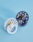 Two baby pacifiers with polka dot designs on a light blue background