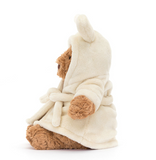 Teddy bear wearing a cream robe on a white background