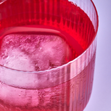 Close-up of a red glass with ice cubes on a light blue background