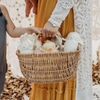 Person holding a wicker basket with plush toys outdoors