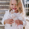 Child holding three plush bunny toys outdoors