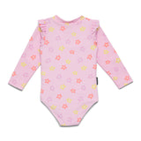 A pink long-sleeve baby swimsuit or bodysuit with a small floral print in yellow, orange, and purple, featuring ruffled shoulders and a high collar, laid flat on a white background.