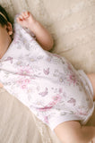 Baby wearing a floral outfit lying on a soft surface