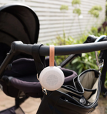 White baby monitor with pink strap attached to a stroller handle