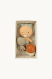 Set of baby toys including a teddy bear, orange ball, and beige rattle in a box on a white background