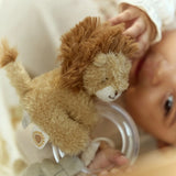 Baby holding a plush lion toy with a soft focus background
