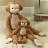 Two plush monkey toys sitting on a carpeted floor.